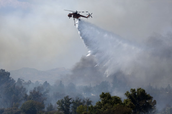 A fire department helicopter makes a water drop over a brush fire at the Sepulveda Basin in Los Angeles on Sunday.
