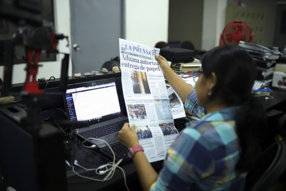 A journalist holds up a copy of La Prensa independent newspaper with a headline that reads in Spanish; "Customs authorises release of printing paper,"   on Friday.