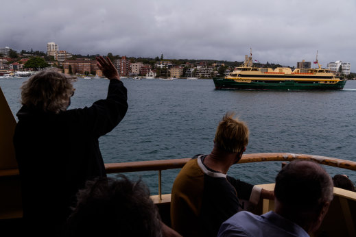 Passengers aboard the Queenscliff wave to her sister the Freshwater during its final voyage on Wednesday.