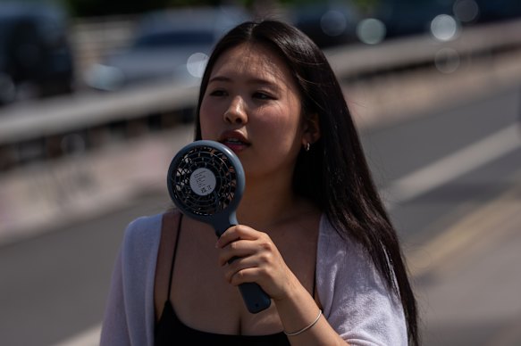 A woman uses a fan to cool herself in London.