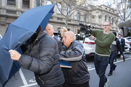 With a relative covering her face with an umbrella, Lydia Abdelmalek is pursued by a press pack as she leaves court on Friday.