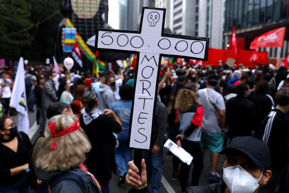 A demonstrator holds a sign in the shape of a cross with the phrase ’500,000 deaths’ during a protest against Bolsonaro’s administration on June 19, 2021 in Sao Paulo, Brazil. 