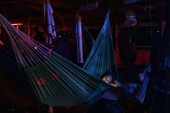 A woman rests in a hammock on an overnight boat journey along the Amazon River to the remote city of Tefé, Brazil.