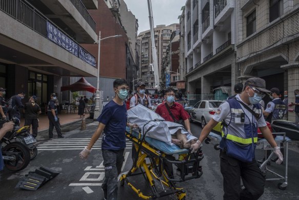 Paramedics transport a dead body from a residential building in the wake of a fire in Kaohsiung, Taiwan. 