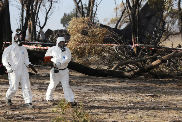 Two ATSB personnel recover the cockpit voice recorder from the wreckage of the C-130, which crashed in southern NSW. 