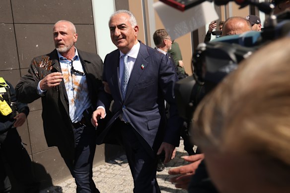 Reza Pahlavi (right), son of the late shah, departs after he was pelted with a substance in Berlin.