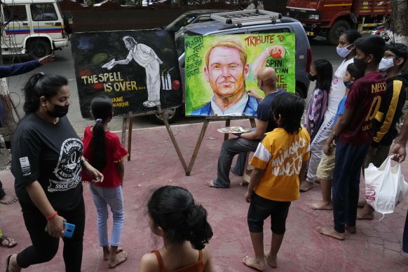 Indian artist Sagar Kambli makes a painting of Australian cricketer Shane Warne as a mark of tribute  on a sidewalk in Mumbai, India.