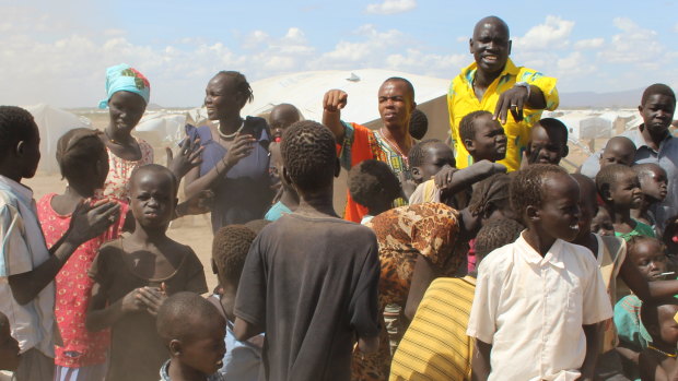 Brisbane's John Yaak, pictured back-right in the yellow shirt, towers above the locals of South Sudan.