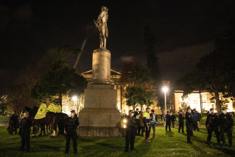 A statue of Captain James Cook under police guard during the Black Lives Matter protest on Friday night.