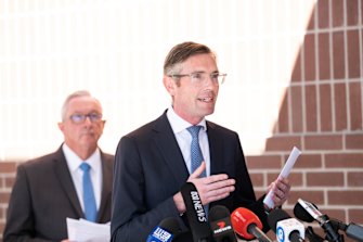 NSW Premier Dominic Perrottet, with Health Minister Brad Hazzard (behind) announcing changes to COVID isolation rules earlier today. 
