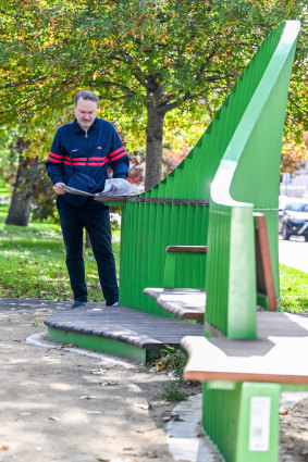A man uses the leaning feature of the Carlton bench.