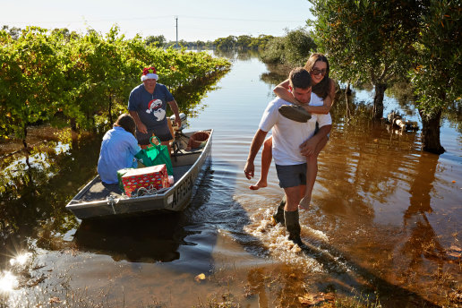 Dreaming of a dry Christmas: Son-in-law Frank Zappia, in boat at rear, and grandchildren Nicolette (in the boat), Joseph and Esta visited Giuseppa and Giuseppe Callipari at their flooded vineyard in Mildura on Christmas morning. 