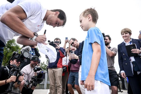 Rafael Nadal signs a hat for a fan at a media event. 
