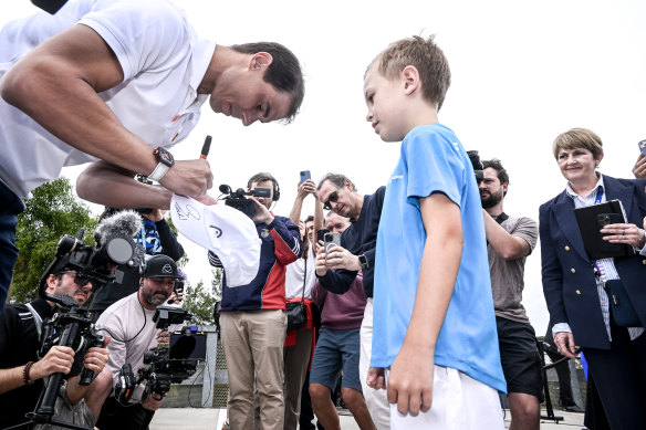 Rafael Nadal signs a hat for a fan at a media event. 