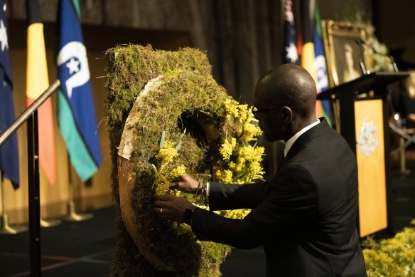 Mourners lay wattle on two wreaths.