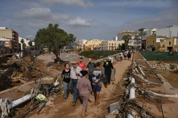 People cross a bridge through piles of debris in Valencia..
