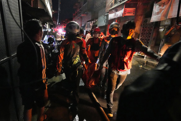 ndonesian rescue team carry a victim of fire at a neighborhood in Jakarta, Indonesia,