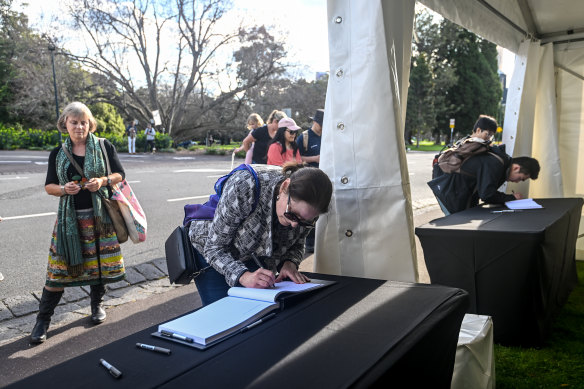 People sign a condolence book at Government House.