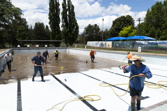 Locals pitch in to clean the muddy Molong Swimming Pool on Tuesday.