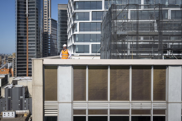 Renovations at the heritage-listed AMP Tower are under way. Aidan Reek, project manager at Built, stands above the gold windows, that were made with real gold leaf.