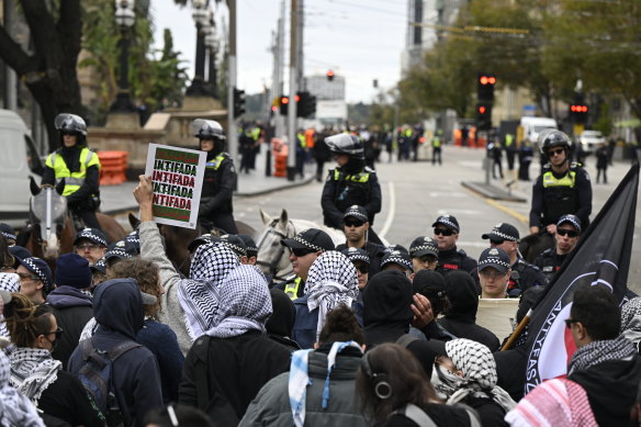 Pro-Palestine protesters are held back by police to stop them approaching a pro-Israel rally in Melbourne on Sunday.