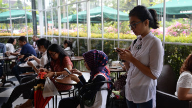 Customers on their phones at a cafe in Jakarta.