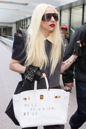 Lady Gaga in 2010, with her Hermes bag scrawled with the Japanese words "little monsters", the term she uses for her fans.