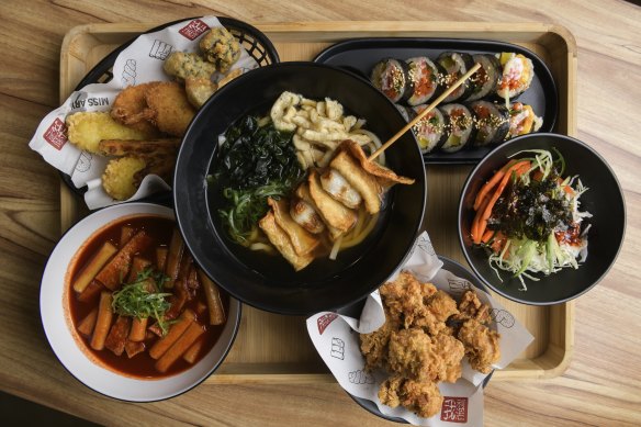 A platter with (clockwise from left) fried basket, fish cake udon soup, kim bab, bibim japchae, original chicken and tok bok ki. 