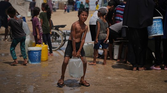 Displaced Palestinians gather to collect water from a truck during a heat wave at a makeshift tent camp in Khan Younis, Gaza Strip on Wednesday.