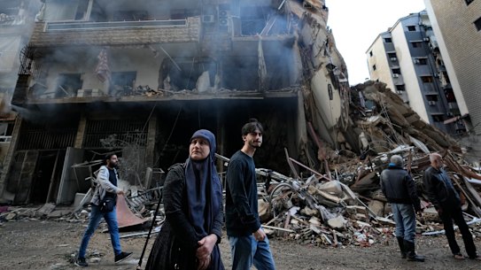 Residents pass in front of destroyed buildings that were hit Sunday night in an Israeli airstrike in Dahiyeh.