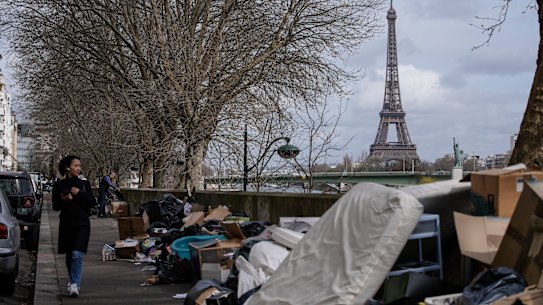 A woman walks past uncollected rubbish in Paris.