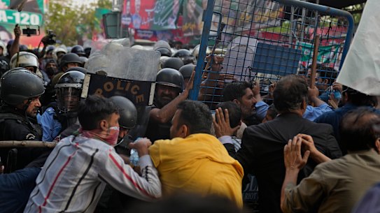 Supporters of former Prime Minister Imran Khan’s party scuffle with riot police officers outside Khan’s residence, in Lahore. An order has been issued for his arrest for failing to appear in court on corruption charges.