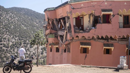 A man stands next to a damaged hotel after the earthquake.