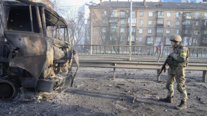 A Ukrainian soldier walks past a burning military truck in Kyiv.