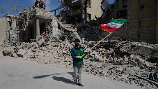 Um menino agita uma bandeira iraniana em frente a uma instalação policial atingida durante a campanha militar EUA-Israel em Teerã, Irã, na quarta-feira.