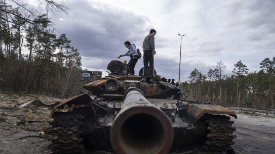 Residents stand on a Russian tank in the outskirts of Kyiv on Monday.