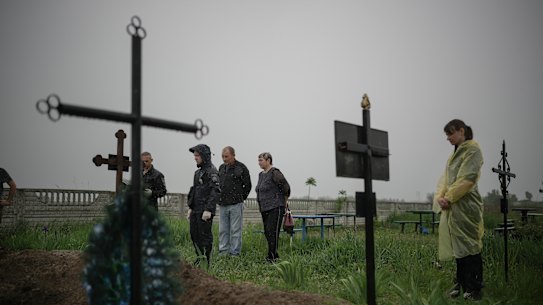 Kuzova village resident, centre, looks on as police exhume the bodies of his mother, brother and son to investigate alleged war crimes by Russian forces during the invasion of Ukraine.