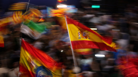 Supporters of Spain’s mainstream conservative Popular Party supporters wave flags.