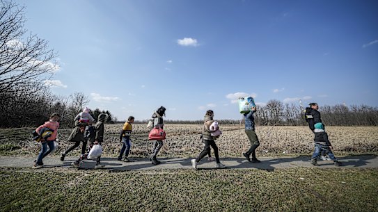 Refugees fleeing Ukraine walk through the Hungarian countryside.