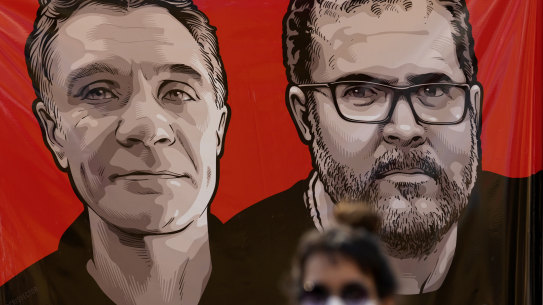 A worker of the National Indian Foundation, FUNAI, stands next to a banner with images of missing Indigenous expert Bruno Pereira, right, and freelance British journalist Dom Phillips, during a vigil in Brasilia, Brazil, on Monday.