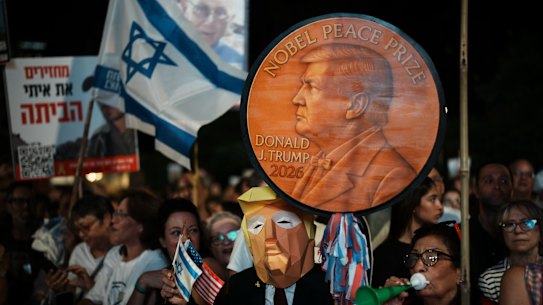 A man wearing a mask resembling US President Donald Trump holds a sign designed like a Nobel Peace Prize medal at a rally in Tel Aviv on Saturday.