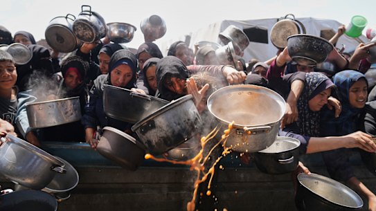 Palestinians struggle to get donated food at a community kitchen in Khan Younis, Gaza Strip.