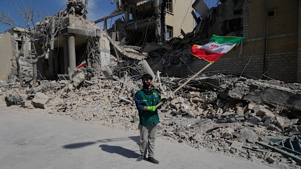 A boy waves an Iranian flag in front a police facility struck during the US-Israeli military campaign in Tehran, Iran, on Wednesday.