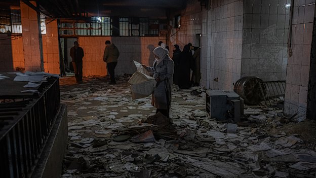 A woman looks over one of many documents and papers strewn about a section of Sednaya, a notorious prison on the outskirts Damascus.