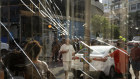 People are seen through a broken window next to the scene of an explosive drone attack in Tel Aviv.