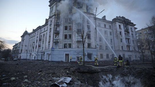 Firefighters work near the crater at the site after Russian attacks in Kyiv, Ukraine, on Thursday.