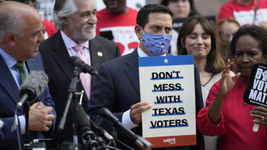 Representative Trey Martinez Fischer holds a sign as he and other Democratic caucus members join a rally on the steps of the Texas Capitol to support voting rights.