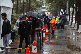 People line up to receive their COVID-19 vaccination despite wet weather at the Sydney Olympic Park Vaccination Centre in Sydney on Tuesday.