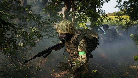 A Ukrainian National Guard serviceman  runs through a tree line during training.