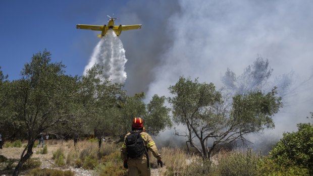 An aircraft drops water over a wildfire in Vati village, on the Aegean Sea island of Rhodes, southeastern Greece.
